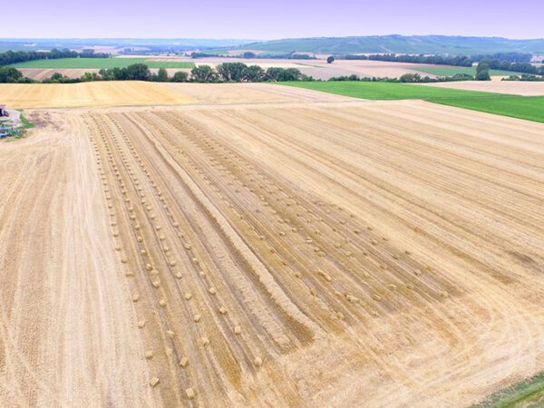 Drone shot of a harvested field with hay bales on farm land.