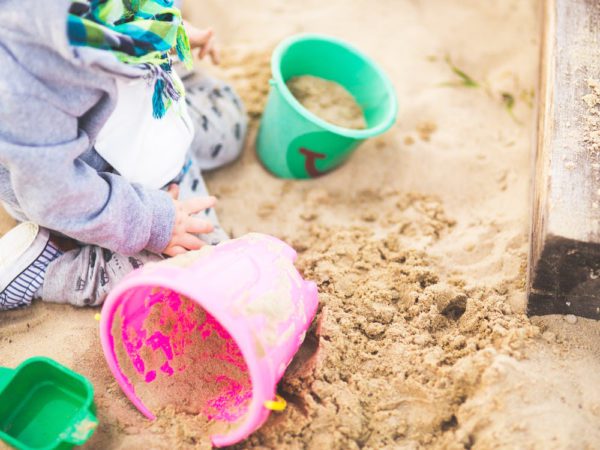 Child playing in sand with sandcastle buckets.