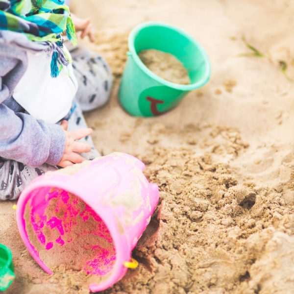 Child playing in sand with sandcastle buckets.