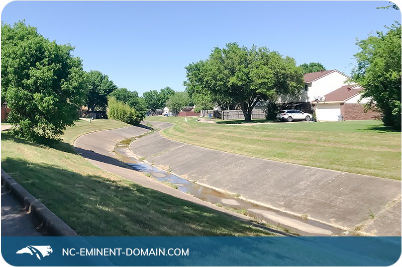 A concrete drainage ditch in the backyard of neighborhood homes.
