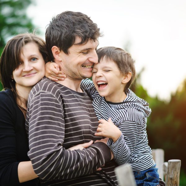 Young child and parents smiling and embracing each other.