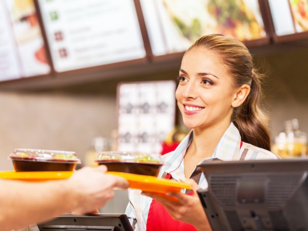 Fast food employee giving tray of food to customer.