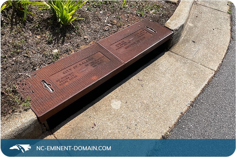 A City of Raleigh storm drain in the concrete curb of a suburban neighborhood.