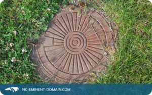 Manhole cover over a sewer in a residential lawn.