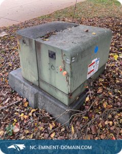 Transformer box in a residential neighborhood, surrounded by fall leaves.